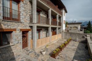 un edificio de piedra con un porche con plantas. en Aparthotel Bellver en Bellver de Cerdanya 