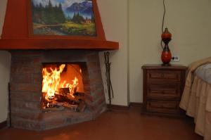 a fireplace in a living room with a fire at Balcones del Río Hotel in Latacunga