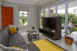 a living room with a couch and a flat screen tv at The Cottage on Cordia 2 Bedroom self catering 2km from Umhlanga beach in Durban