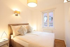 um quarto com uma cama com lençóis brancos e uma janela em Honey-Sorgatina em Colmar