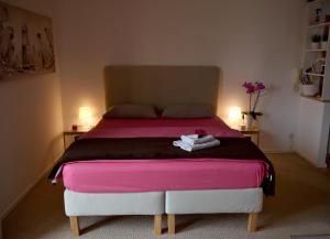 a bedroom with a bed with pink sheets and two lamps at Studio apartman D in Sesvete