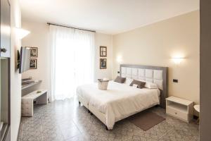 a white bedroom with a large bed and a window at Hotel Le Vigne di Corvino in Casteggio