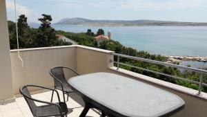 a table and chairs on a balcony with a view of the water at Apartmani Luna in Novalja