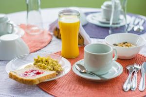 einen Tisch mit einem Teller Essen und einer Tasse Orangensaft in der Unterkunft Ponta Da Barca in Praia Vermelha