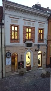 biały budynek z oknami wychodzącymi na ulicę w obiekcie Kisfaludy Károly Apartman w Győr