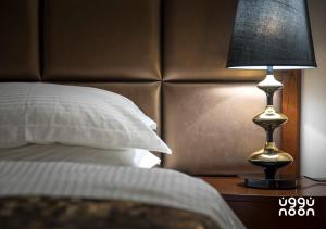 una cama con una lámpara negra en una mesita de noche junto a una cama en Noon Hotel Suites, en Al Khafji