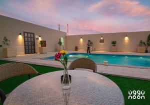 a table with a vase of flowers on top of a pool at Noon Hotel Suites in Khafji