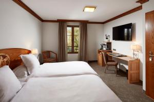 エンシスハイムにあるHotel Spa Restaurant Domaine du Moulinのベッド2台とデスクが備わるホテルルームです。