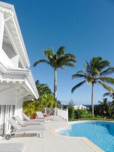 a white house with a swimming pool and palm trees at H&ocirc;tel Amaudo in Saint-Fran&ccedil;ois
