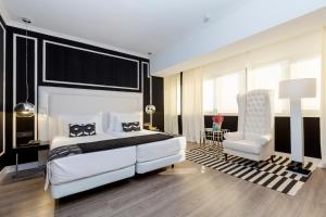 een slaapkamer met een groot wit bed en een stoel bij Hotel Tres Reyes Pamplona in Pamplona