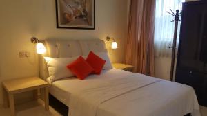 ein Schlafzimmer mit einem weißen Bett mit zwei roten Kissen in der Unterkunft Kurau Inn Boutique Farmstay in Kuala Kurau