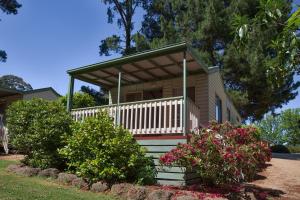 a small house with a porch and some flowers at Daylesford Holiday Park in Daylesford