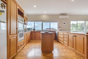 a large kitchen with wooden cabinets and windows at Serpentine Rose in Albany