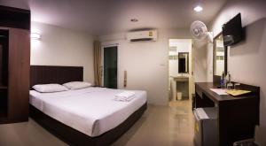 a bedroom with a white bed and a television at Sunshine Hostel in Hua Hin