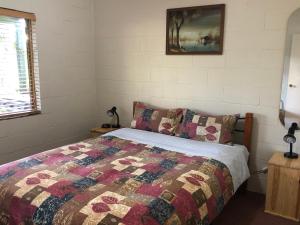 a bedroom with a bed with a quilt on it at Country Cottages of Bridgetown in Bridgetown