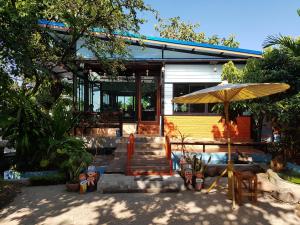 a house with a patio with an umbrella at Sun smile(cafe & homestay) in Ubon Ratchathani