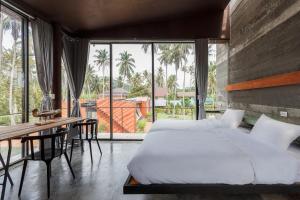 een slaapkamer met een bed, een bureau en een groot raam bij Coconutnoom Ko Phangan in Thongsala