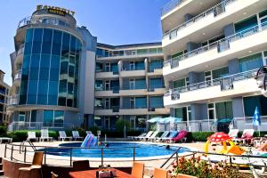 a hotel with a pool and chairs and a building at Favorit Aparthotel in Sunny Beach