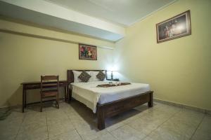 - une chambre avec un lit, une chaise et un bureau dans l'établissement Tegar Guest House Ubud, à Ubud