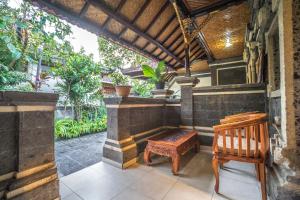 un porche con una silla de madera y un banco en Tegar Guest House Ubud, en Ubud
