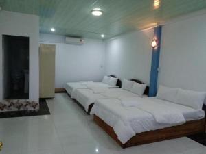 Duas camas num quarto com paredes brancas em Silver Dolphin Guesthouse & Restaurant em Kratié