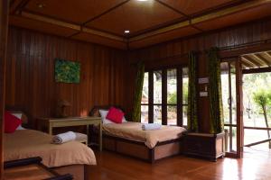 two beds in a room with wooden walls and windows at Indie House @ Maerim in Mae Rim