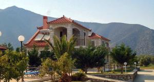 a large building with a mountain in the background at Glyfada Villas || in Paralion astros