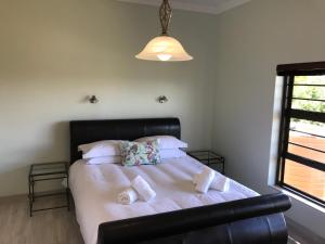 a bedroom with a bed with white sheets and pillows at Sandy Bottoms in Jeffreys Bay
