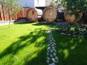 a yard with green grass and some wooden barrels at Zozo House in Braşov