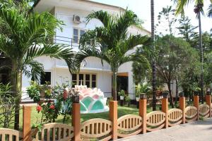 a fence in front of a house with palm trees at Green Grass Hotel & Restaurant in Jaffna