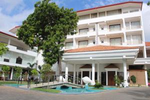 un grand bâtiment blanc avec un arbre en face dans l'établissement The Valampuri, à Jaffna