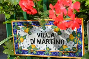 a sign that says villa daminato with red flowers at Villa Di Martino in Sant'Egidio del Monte Albino