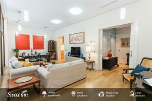 Alameda de Hercules Apartment في إشبيلية: غرفة معيشة مع كنبتين بيضاء وطاولة