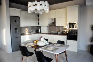 cocina con armarios blancos, mesa y sillas en Rubio Residence - Frateria Apartment, en Arad