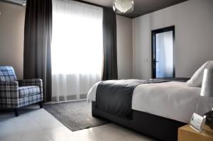 a bedroom with a bed and a chair and a window at Rubio Residence - Frateria Apartment in Arad