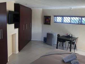 a bedroom with a bed and a table and a television at Flamingo Palms in Table View