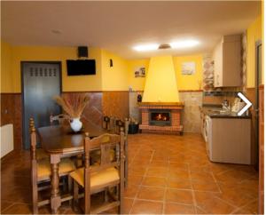 a kitchen and dining room with a table and a fireplace at El Encanto de la Villa in Rades de Abajo