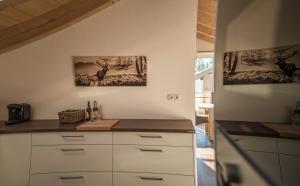 ヴァルガウにあるAlpenwohnung Neunerの白いキャビネットと壁に2枚の絵が飾られたキッチン