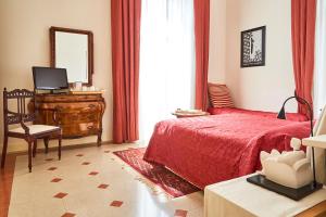 una camera con letto rosso, cassettiera e specchio di Suite Klimt P.zza Amedeo a Napoli