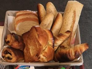 a tray filled with bread and pastries and breadsticks at Les Roses Des Bois in Murat-le-Quaire