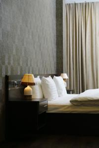 - une chambre avec un lit doté d'oreillers blancs et d'une lampe dans l'établissement Tomu's Hotel, à Gyumri