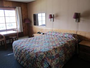 Habitación de hotel con cama, mesa y ventana en Lakeside Motel, en Williams Lake