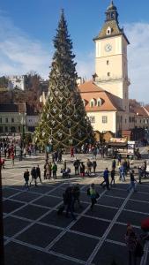 Un gruppo di persone intorno a un albero di Natale di fronte a un edificio di 4 Rooms Piata Sfatului a Braşov