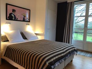 1 dormitorio con 1 cama con manta a rayas en blanco y negro en Le Jardin Des Sources, en La Hulpe