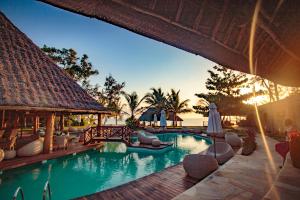 a swimming pool with chairs and umbrellas in a resort at Tulia Zanzibar Unique Beach Resort in Pongwe