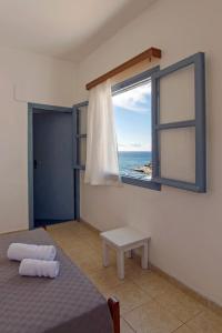 a bedroom with a bed and a window with the ocean at Perigiali Rooms & Apartments Folegandros in Agali