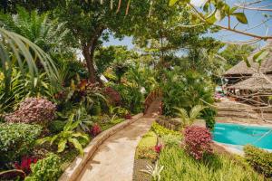 a garden with a swimming pool and plants at Tulia Zanzibar Unique Beach Resort in Pongwe