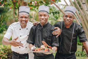 two men in chefsuits holding a plate of food at Tulia Zanzibar Unique Beach Resort in Pongwe