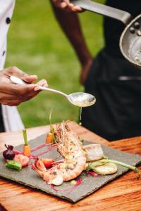 a person holding a spoon over a plate of food at Tulia Zanzibar Unique Beach Resort in Pongwe