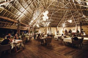 a restaurant with tables and people sitting at tables at Tulia Zanzibar Unique Beach Resort in Pongwe